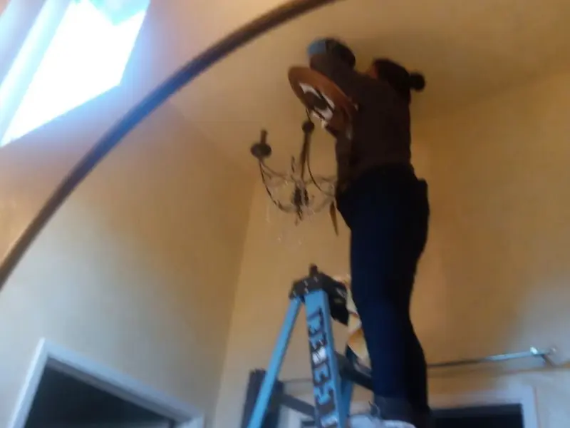 Electrician installing a chandelier in a Bristow residence